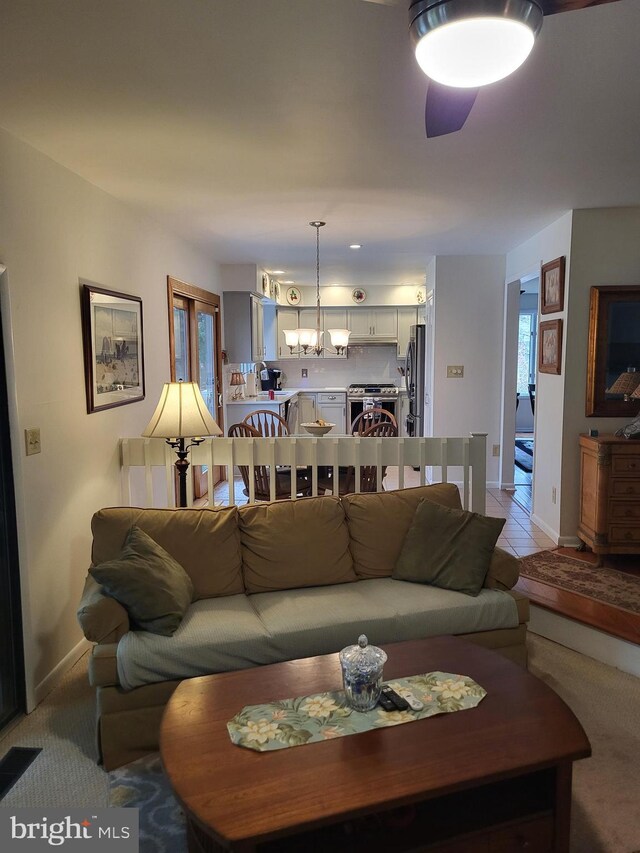 carpeted living room with ceiling fan with notable chandelier