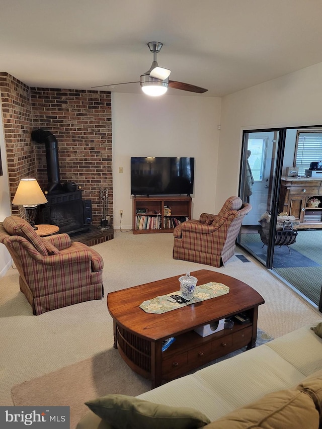 carpeted living room featuring a wood stove and ceiling fan