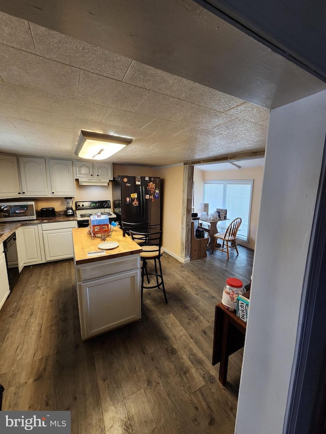 kitchen featuring dark wood-type flooring, white cabinetry, wooden counters, a center island, and black appliances