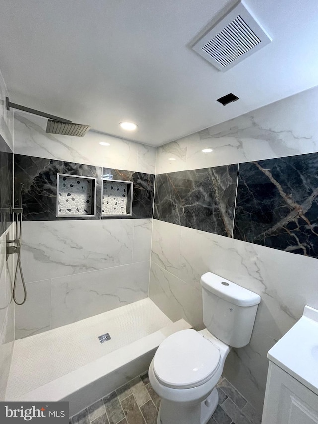 bathroom featuring tiled shower, vanity, and toilet