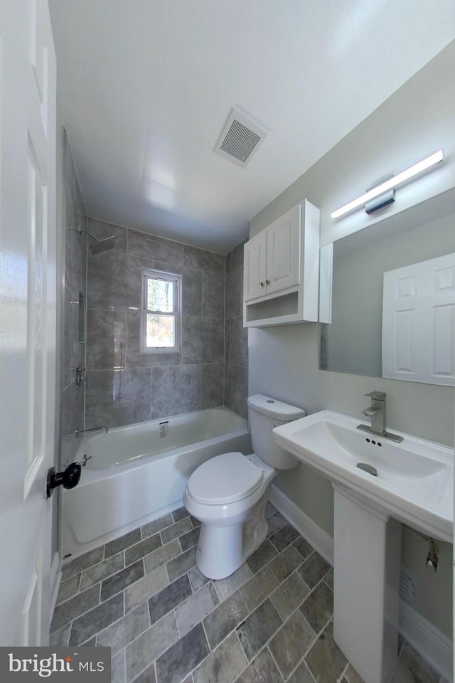 bathroom featuring visible vents, toilet, a sink, shower / tub combination, and baseboards