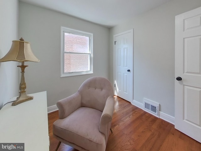 sitting room with visible vents, baseboards, and wood finished floors