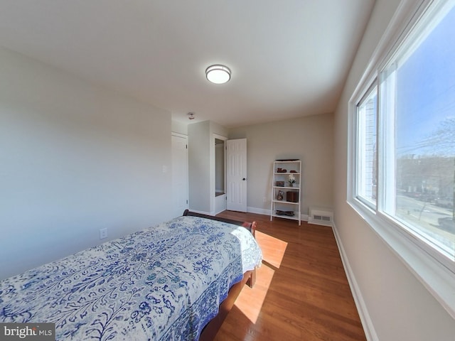 bedroom featuring visible vents, baseboards, and wood finished floors