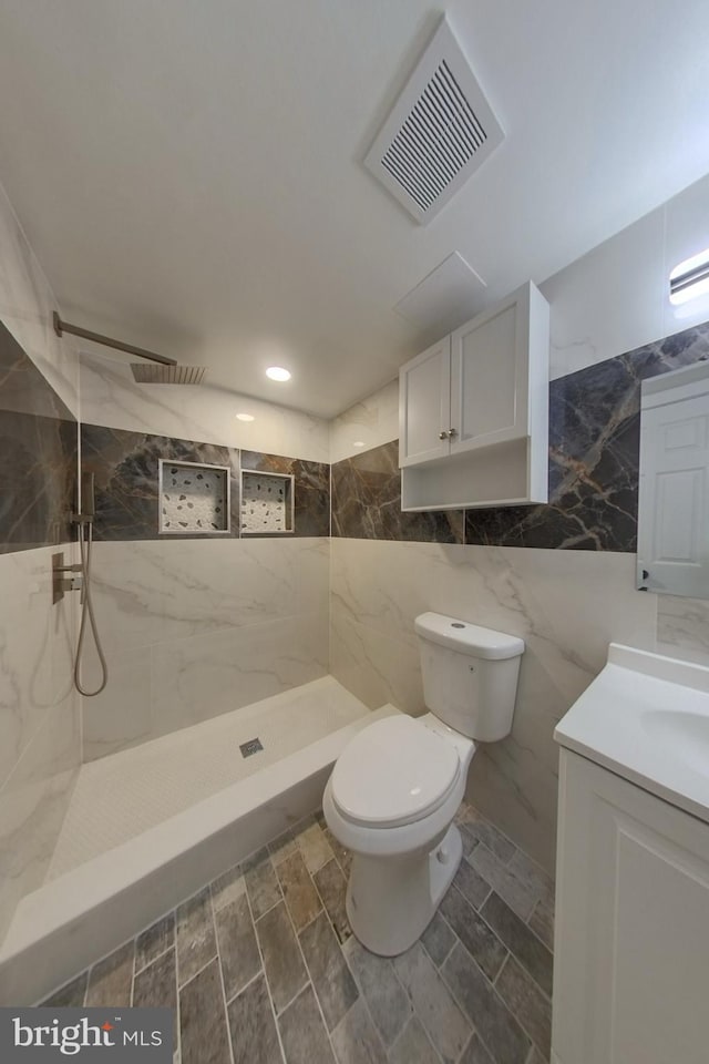 full bathroom with vanity, visible vents, walk in shower, tile walls, and toilet