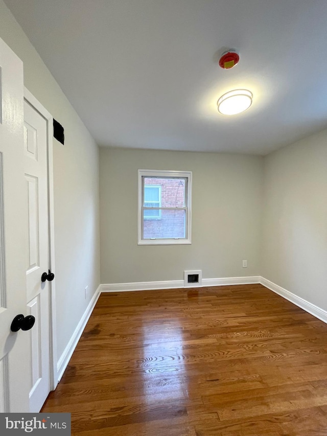 unfurnished room with visible vents, baseboards, and wood finished floors