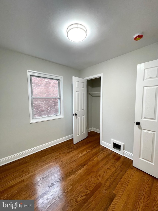 unfurnished bedroom featuring visible vents, dark wood-style flooring, and baseboards