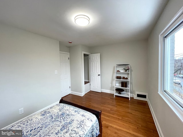 bedroom with visible vents, wood finished floors, and baseboards