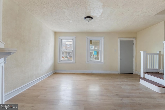 unfurnished living room with a textured ceiling and light wood-type flooring