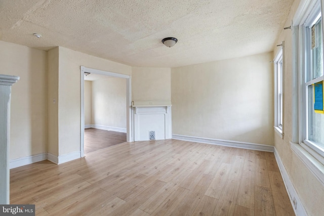 unfurnished living room featuring light hardwood / wood-style flooring and a textured ceiling