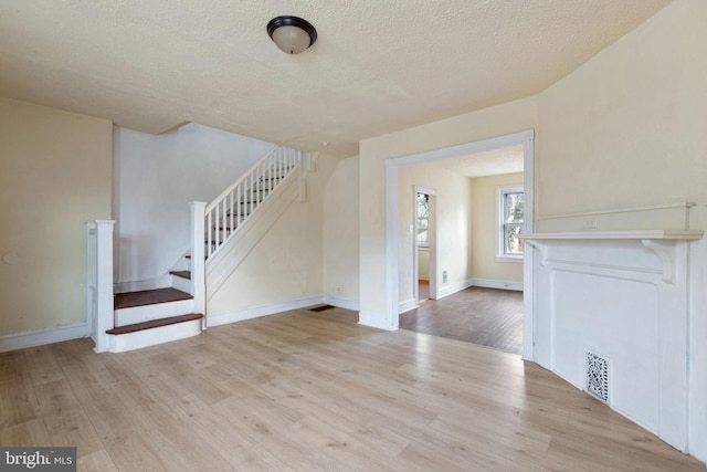 unfurnished living room with a textured ceiling and light wood-type flooring