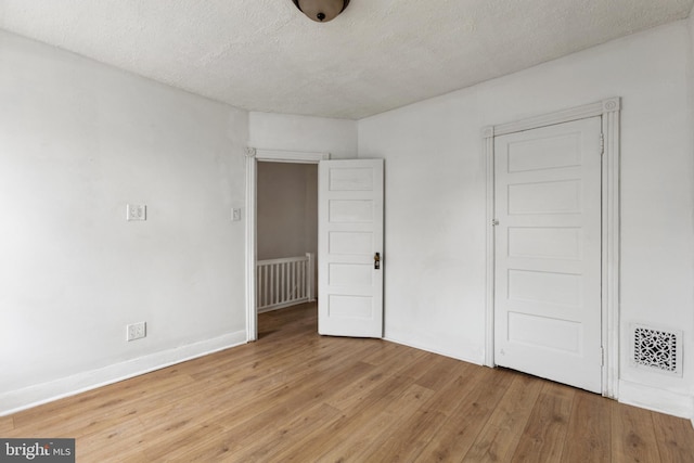 unfurnished bedroom with light wood-type flooring and a textured ceiling