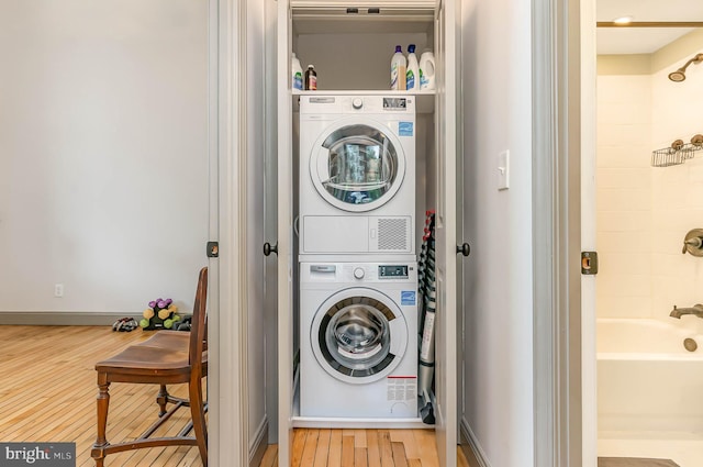 laundry area featuring stacked washer and dryer and wood-type flooring