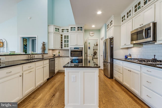 kitchen with dark stone counters, sink, light hardwood / wood-style floors, appliances with stainless steel finishes, and a kitchen island