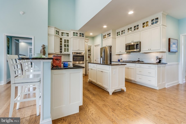 kitchen with appliances with stainless steel finishes, white cabinetry, and a kitchen island