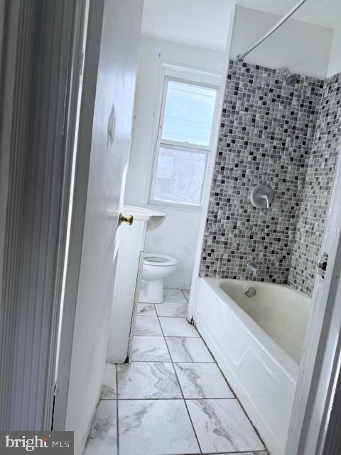 bathroom with tiled shower / bath combo and toilet