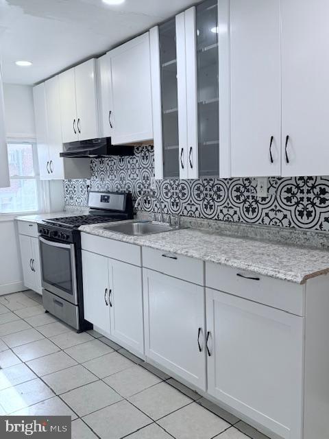 kitchen with white cabinets, stainless steel range with gas cooktop, light stone countertops, and sink