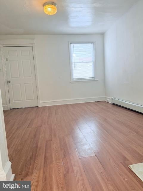 empty room featuring a baseboard heating unit and light wood-type flooring