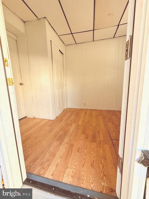 interior space with a drop ceiling and hardwood / wood-style floors