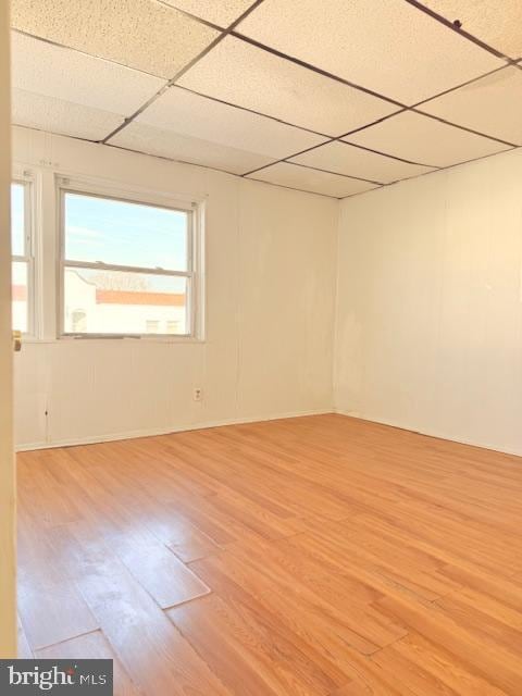 spare room featuring a drop ceiling and light wood-type flooring