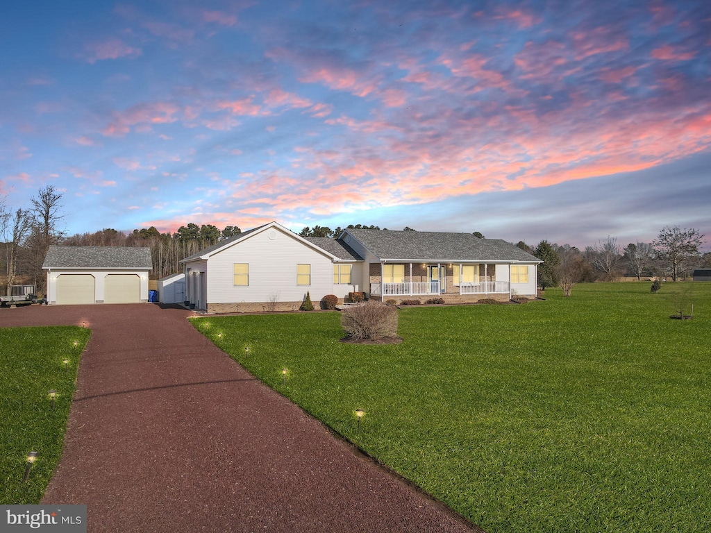 ranch-style home featuring a yard, an outbuilding, a porch, and a garage