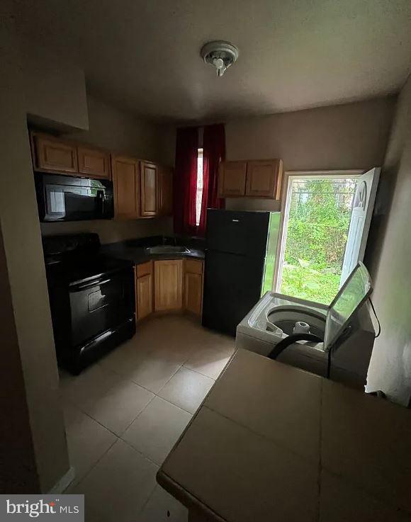 kitchen featuring light tile patterned floors, sink, and black appliances