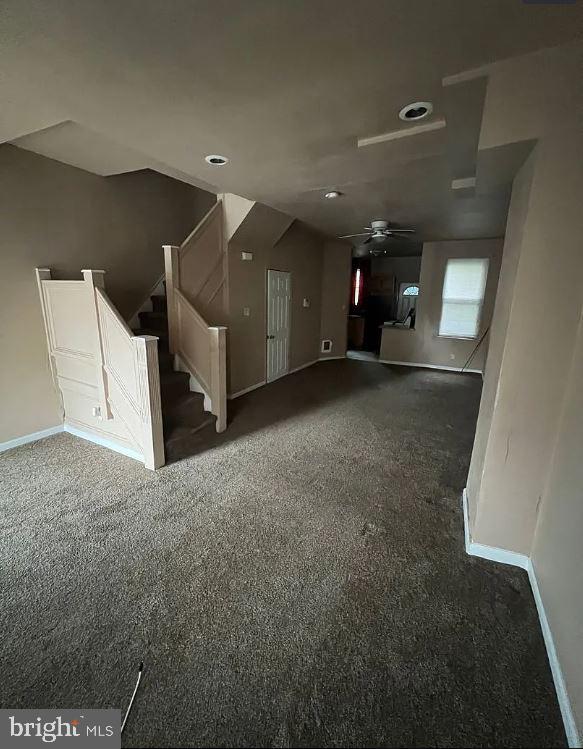 unfurnished living room with dark carpet and ceiling fan