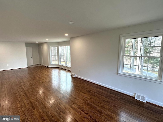 empty room with dark hardwood / wood-style flooring and plenty of natural light