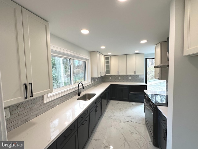 kitchen featuring light stone countertops, tasteful backsplash, a wealth of natural light, sink, and white cabinetry