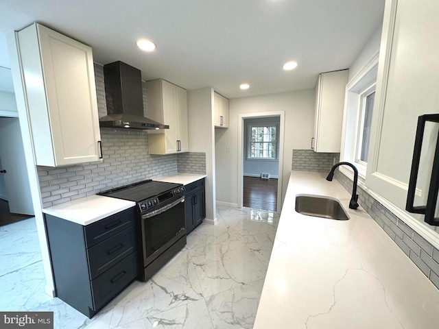 kitchen featuring backsplash, sink, wall chimney range hood, electric range, and white cabinetry