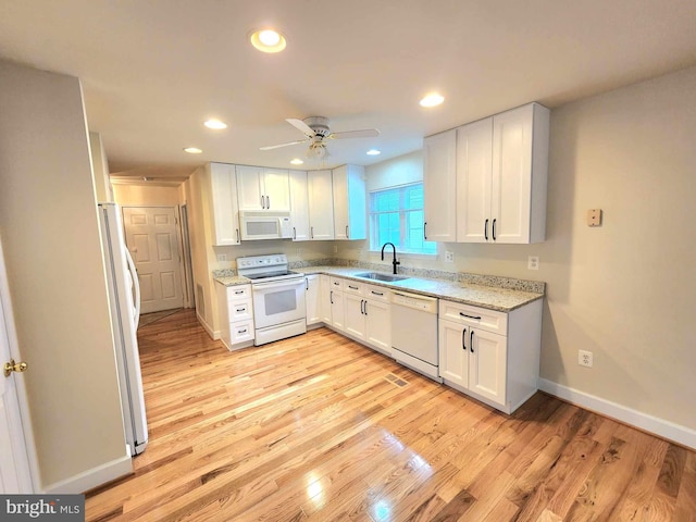 kitchen featuring white cabinets, white appliances, light stone countertops, and sink