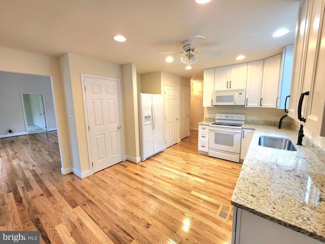 kitchen featuring white appliances, white cabinets, sink, light hardwood / wood-style floors, and light stone counters