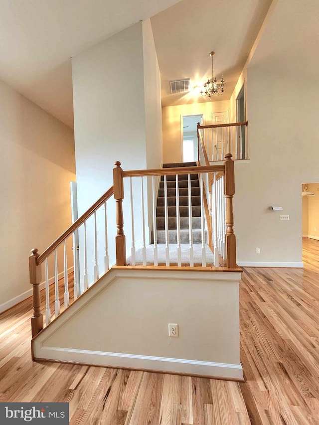 staircase with a chandelier and wood-type flooring