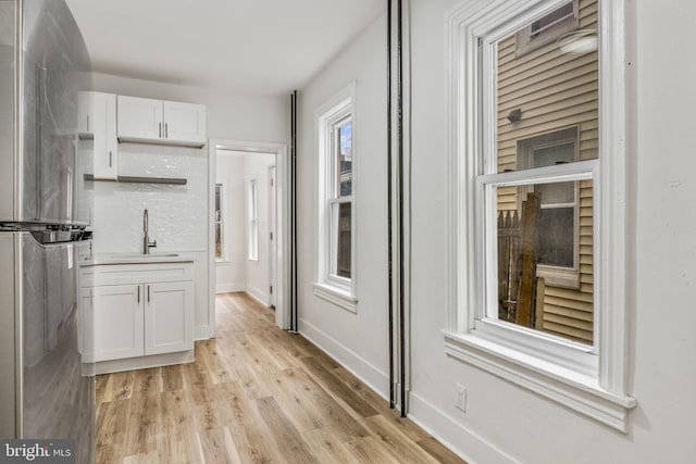 kitchen with white cabinets, light wood-type flooring, a wealth of natural light, and sink