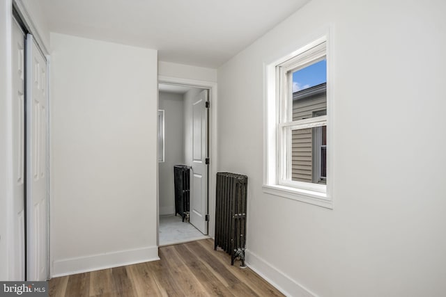 hall with radiator heating unit, plenty of natural light, and wood-type flooring