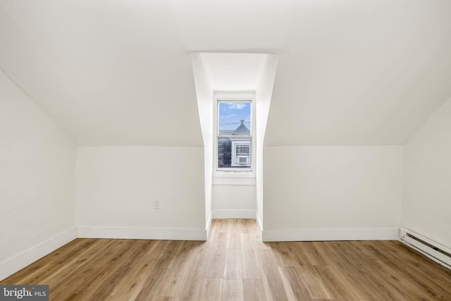 additional living space featuring baseboard heating, light hardwood / wood-style floors, and lofted ceiling