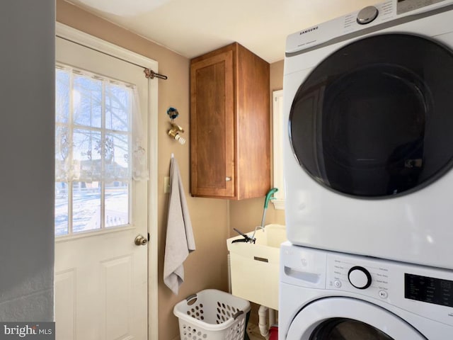 laundry room featuring cabinets and stacked washer / dryer