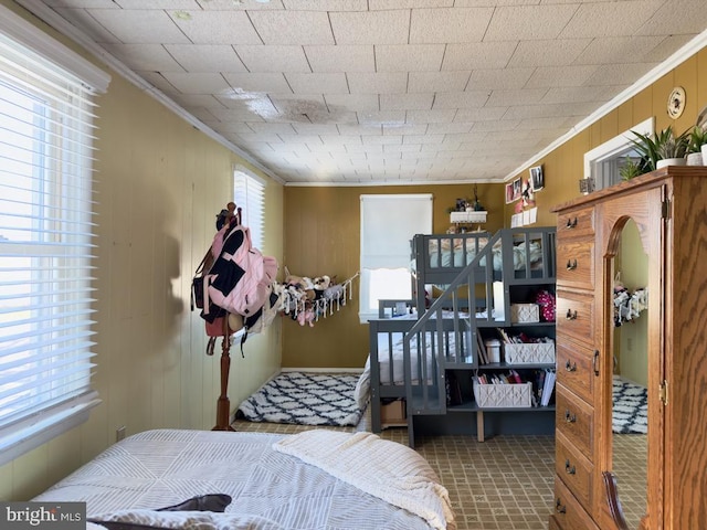 bedroom with ornamental molding and wooden walls