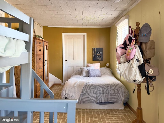 bedroom featuring crown molding and wooden walls