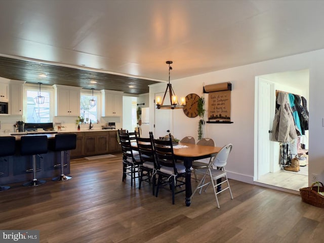 dining room featuring dark wood-type flooring, a chandelier, and sink