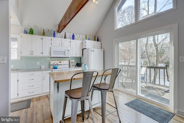 kitchen with white cabinets, white appliances, a breakfast bar area, and tasteful backsplash