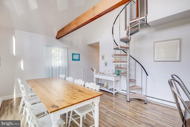 dining area featuring vaulted ceiling with beams, a textured ceiling, and light wood-type flooring