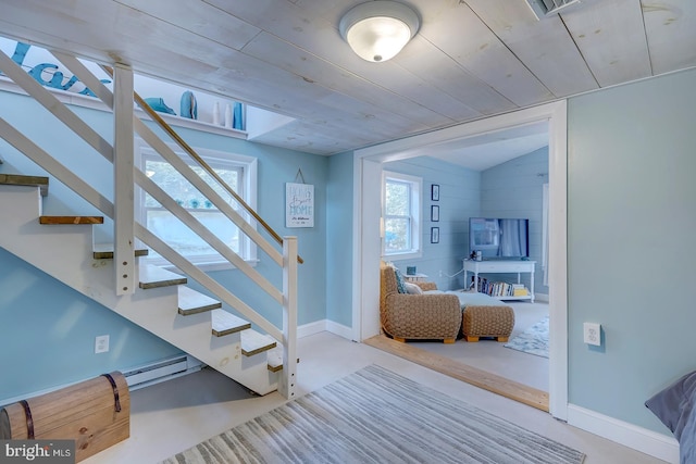 stairway with wooden ceiling, concrete floors, and a healthy amount of sunlight