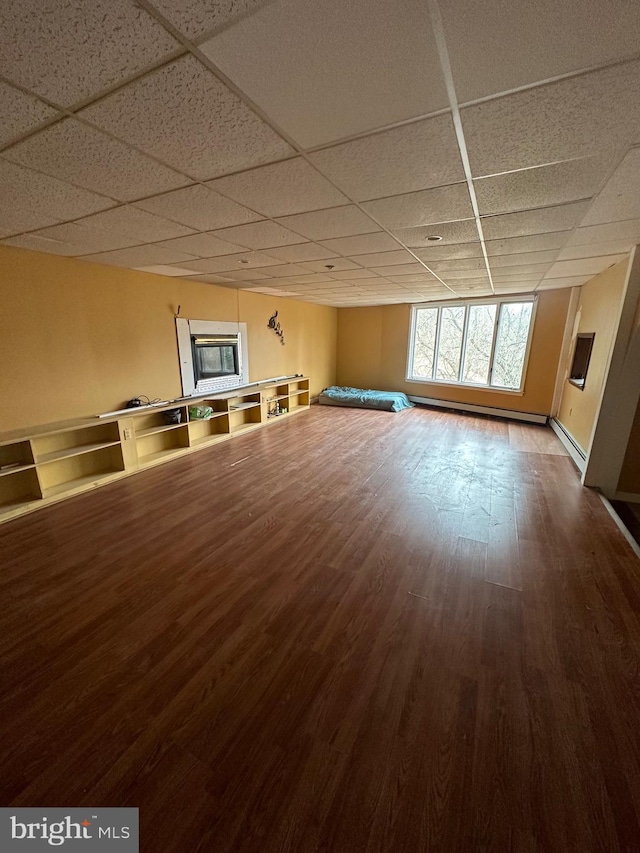 interior space featuring hardwood / wood-style flooring, a baseboard radiator, and a drop ceiling