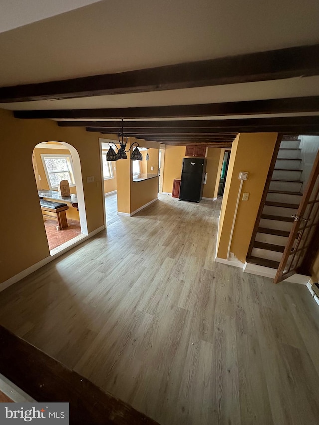 interior space featuring beam ceiling, an inviting chandelier, and light wood-type flooring