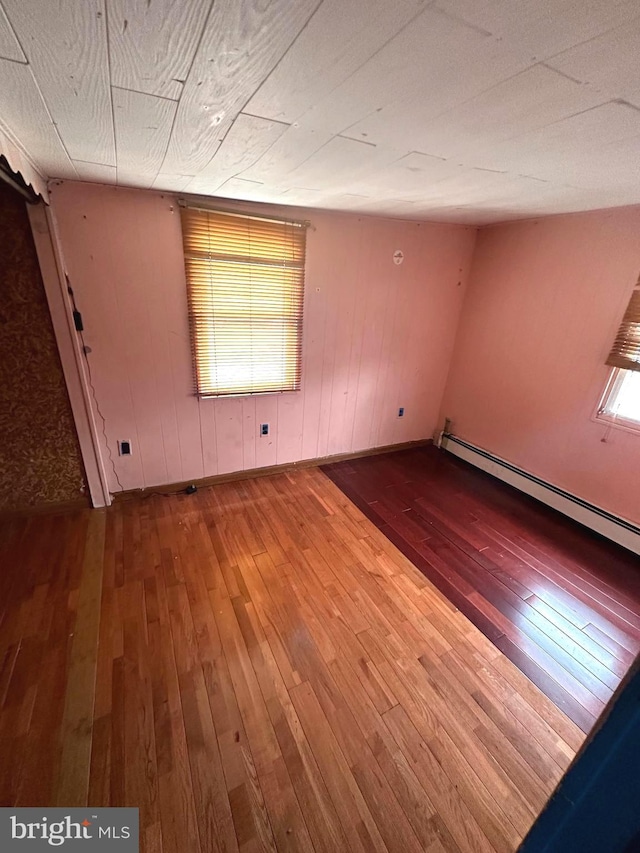 spare room featuring hardwood / wood-style flooring and a baseboard heating unit