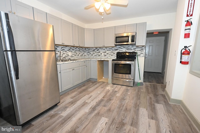 kitchen with decorative backsplash, light wood-type flooring, stainless steel appliances, sink, and gray cabinets