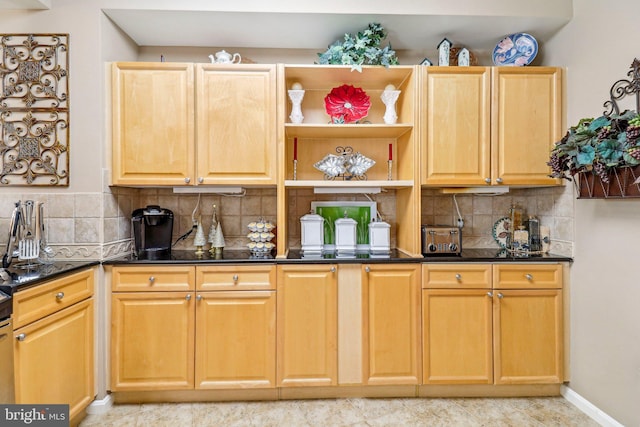 kitchen with light brown cabinets, dark stone countertops, and tasteful backsplash