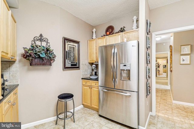 kitchen with decorative backsplash, stainless steel refrigerator with ice dispenser, a textured ceiling, and light brown cabinetry