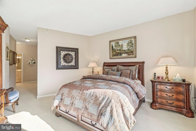 bedroom with connected bathroom and light colored carpet