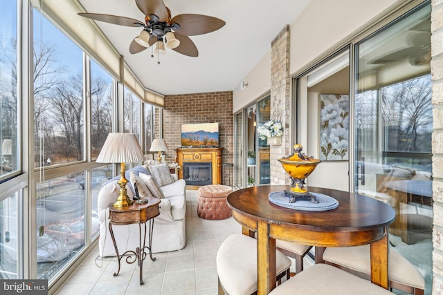 sunroom with ceiling fan and a brick fireplace